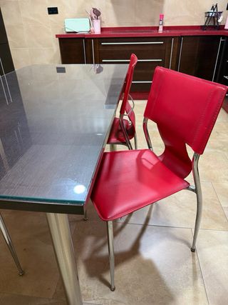 Mesa de comedor con 4 sillas rojas.