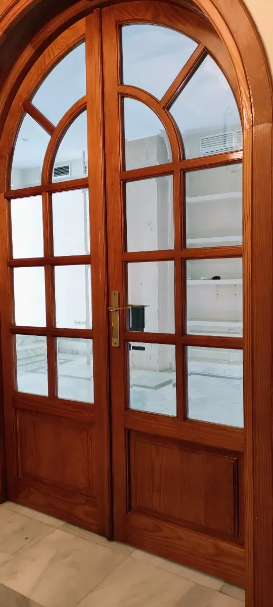 Puerta de madera con arco de medio punto y cristal