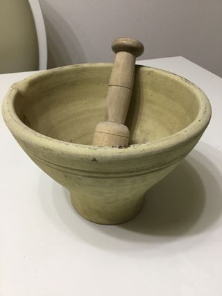 Antiguo mortero de barro con mano de madera