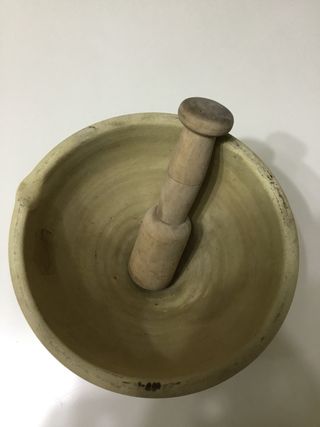 Antiguo mortero de barro con mano de madera