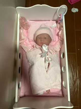 Cuna de juguete con muñecos y accesorios.