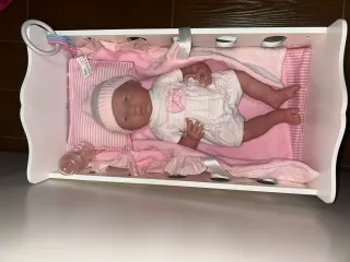 Cuna de juguete con muñecos y accesorios.