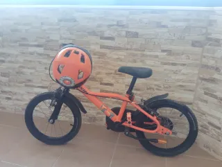 Bicicleta infantil naranja con casco