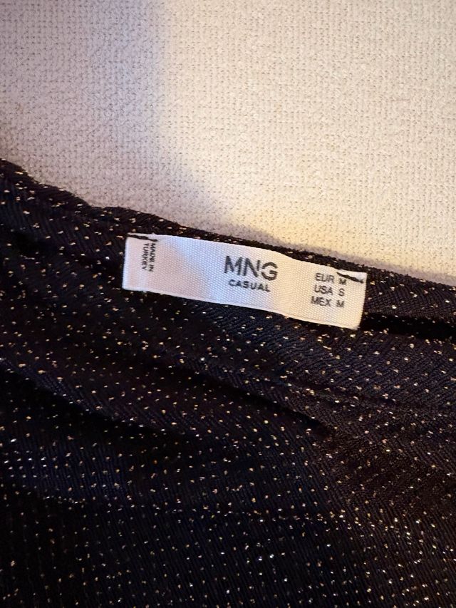 Top asimétrico negro con brillos dorados