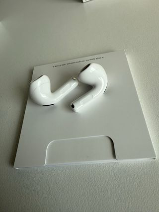 AirPods 4 Blancos con funda azul de regalo.