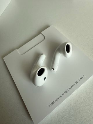 AirPods 4 Blancos con funda azul de regalo.