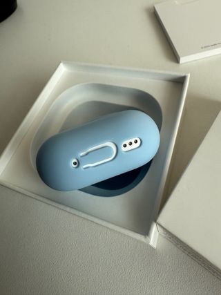AirPods 4 Blancos con funda azul de regalo.