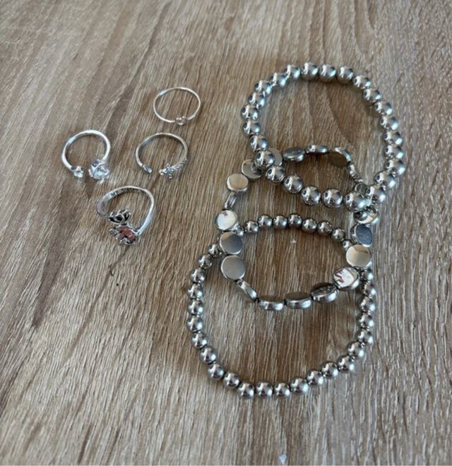 Conjunto de pulseras y anillos plateados
