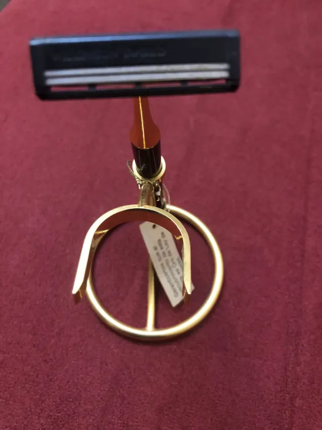 Maquinilla de afeitar dorada con soporte