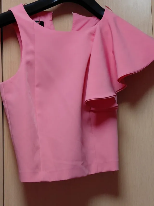 Blusa rosa con volante en la manga.