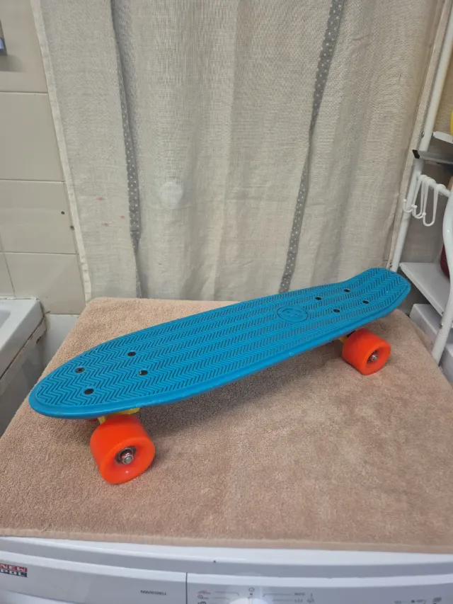 Monopatín azul con ruedas naranjas
