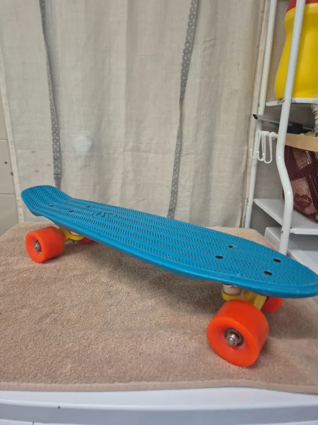 Monopatín azul con ruedas naranjas
