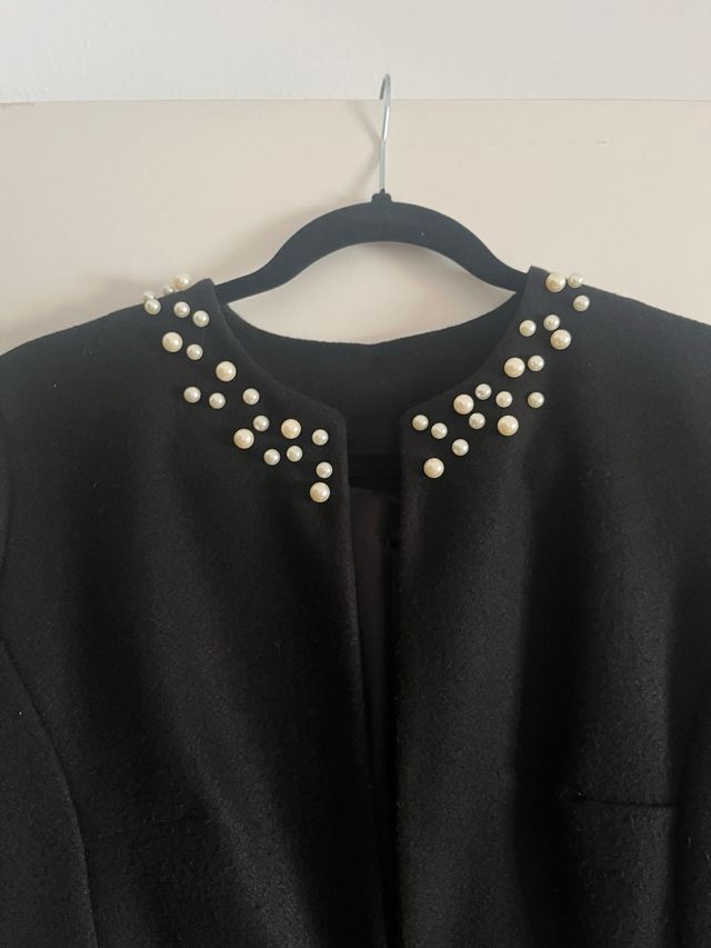 Abrigo negro mujer perlas.