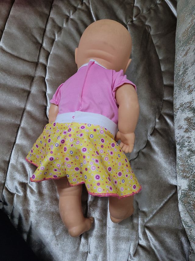 Muñeca bebé con vestido rosa y falda