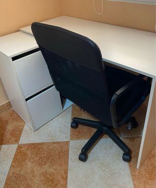 Escritorio blanco con cajones, estantería y silla.