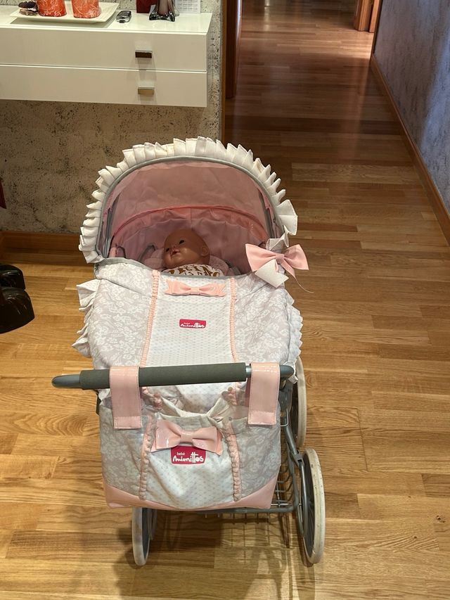 Cochecito de muñecas rosa con muñeco
