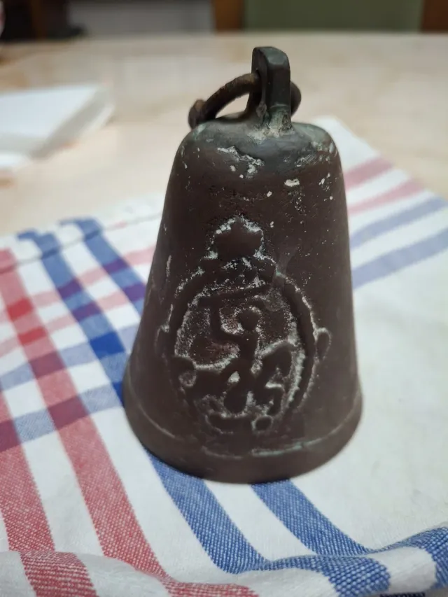 Campana antigua de bronce con símbolo