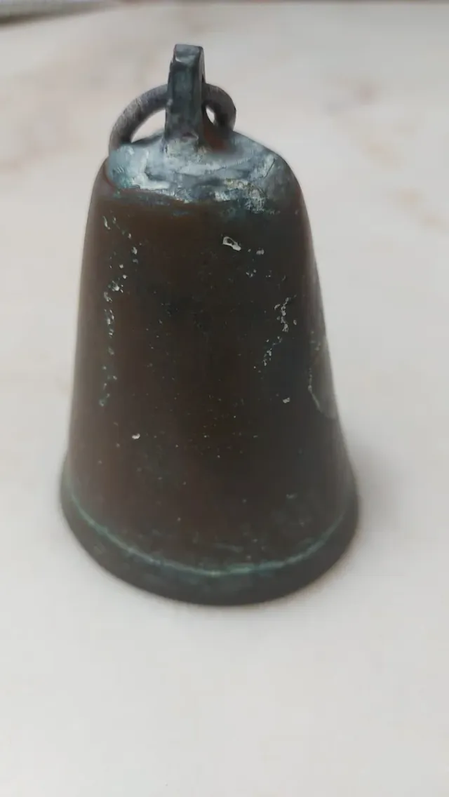 Campana antigua de bronce con símbolo