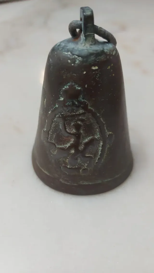 Campana antigua de bronce con símbolo
