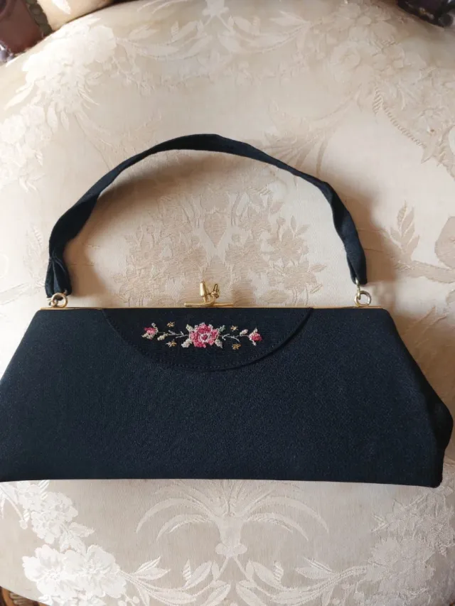 Bolso de mano negro con flores rosas