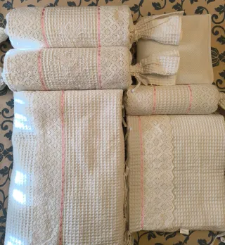 Ropa de cuna de piqué con cintas rosas.