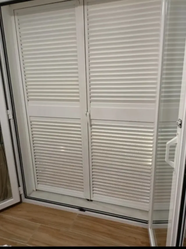 Puerta doble aluminio abatible con veneciana.