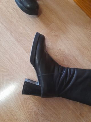 Botas altas de tacón negras. Son de piel.