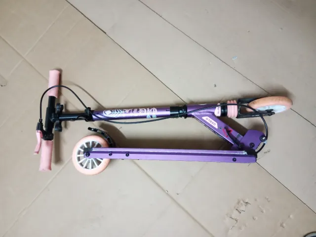 Patinete morado con ruedas naranjas