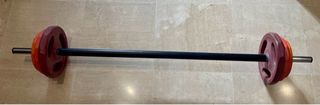 Barra de pesas con discos y topes.