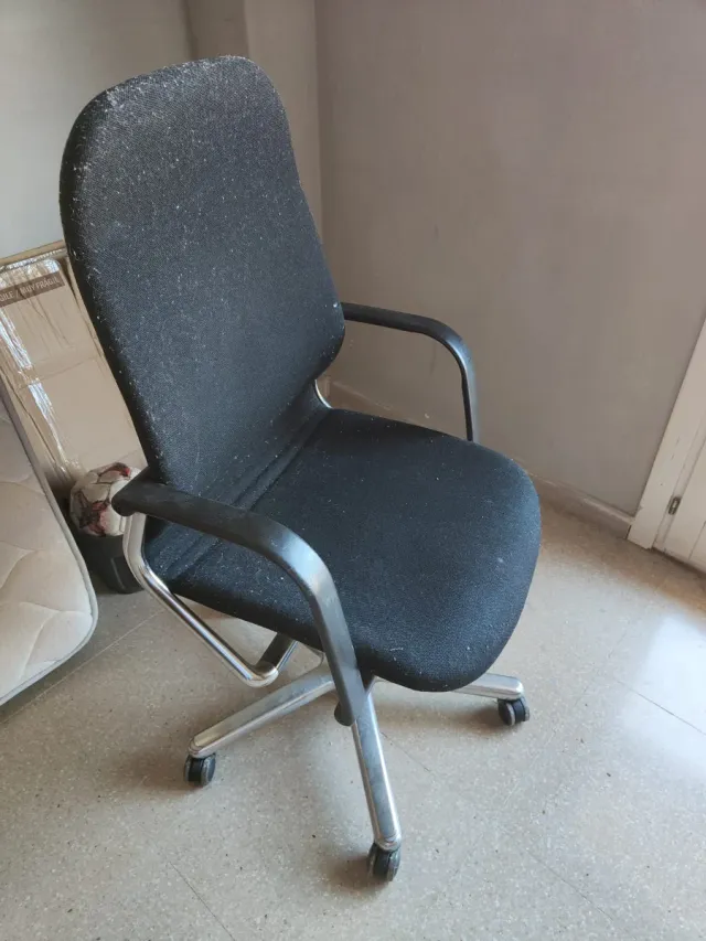 Silla de escritorio negra y plateada con ruedas.