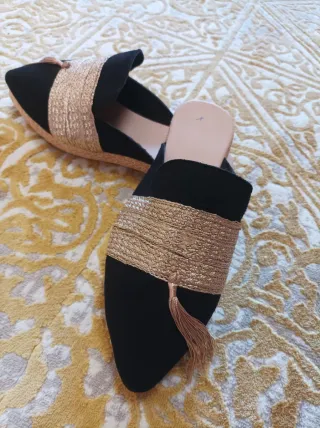 Zapatos planos negros y dorados con flecos