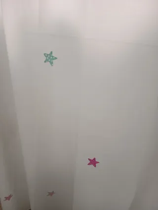 Cortinas blancas con estrellas de colores.