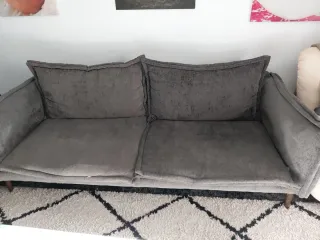 Sofá gris de tela y cojines rellenos de plumas