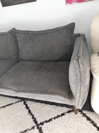 Sofá gris de tela y cojines rellenos de plumas