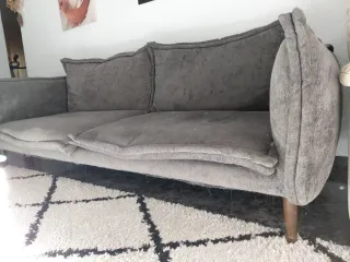 Sofá gris de tela y cojines rellenos de plumas