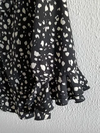 Blusa negra con lunares blancos y volantes.