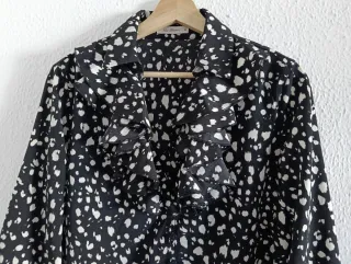 Blusa negra con lunares blancos y volantes.