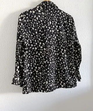 Blusa negra con lunares blancos y volantes.