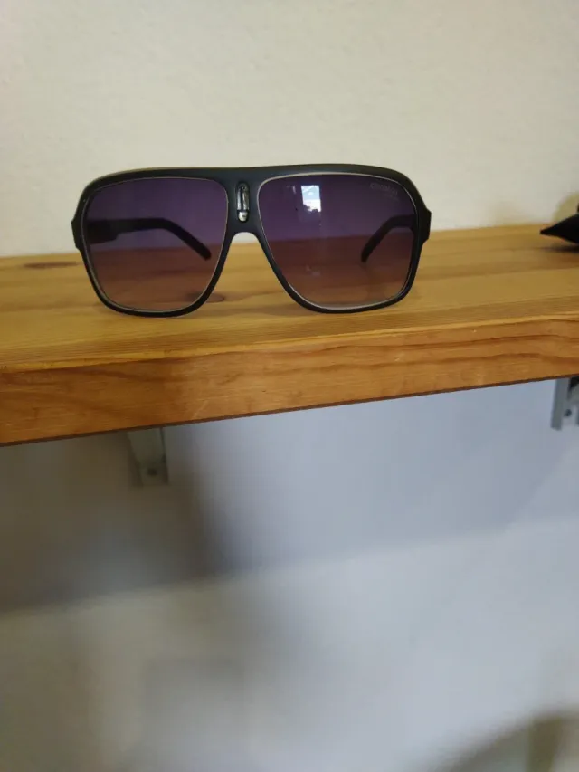 Gafas de sol Carrera negras y moradas en mano