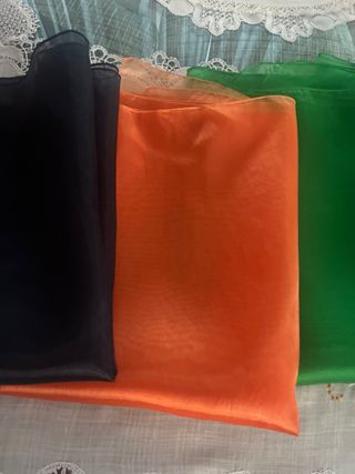 Fulares de tela azul, verde y naranja sin usar.