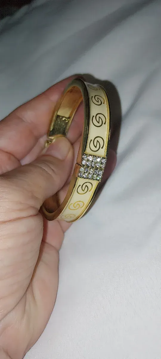 Pulsera rígida dorada con dibujo de eslabones y pe