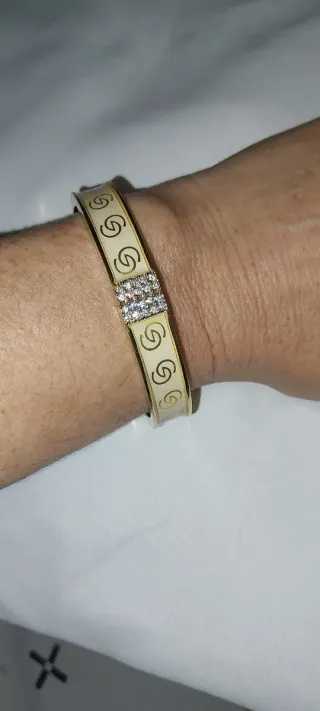 Pulsera rígida dorada con dibujo de eslabones y pe