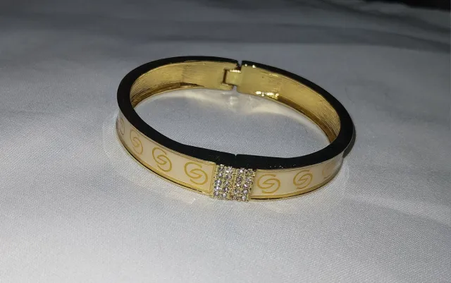 Pulsera rígida dorada con dibujo de eslabones y pe