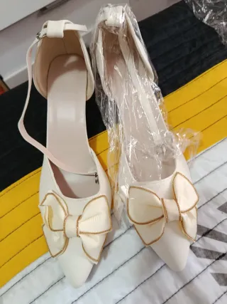 Zapatos de tacón blancos con lazo dorado