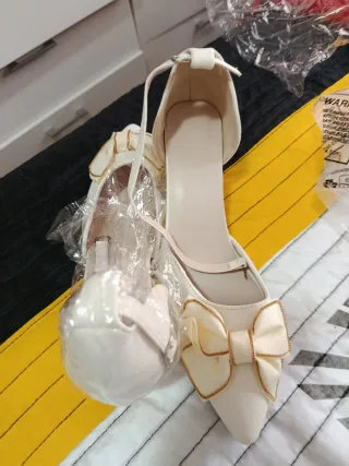 Zapatos de tacón blancos con lazo dorado
