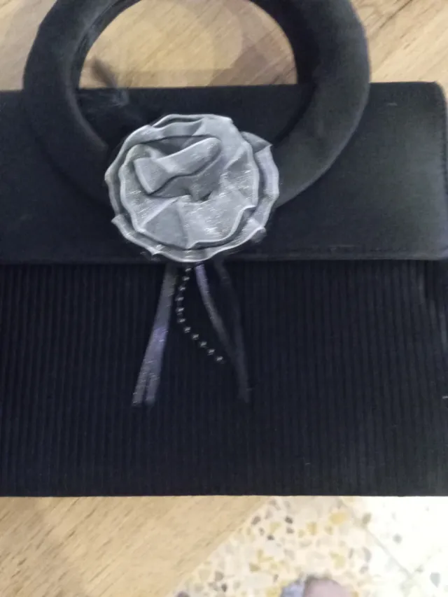 Bolso de mano negro con flor gris