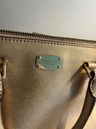 Bolso Michael Kors Dorado. Pequeño mano y cruzado.