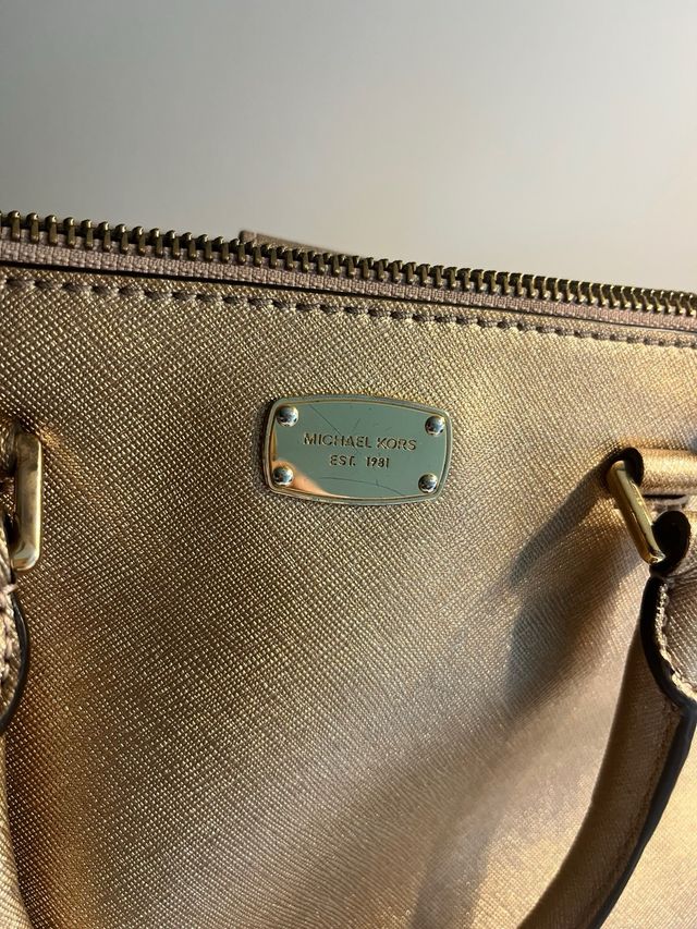Bolso Michael Kors Dorado. Pequeño mano y cruzado.