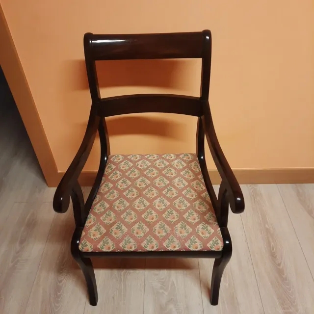 Sillas de madera con brazos y tapizado floral.