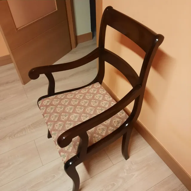Sillas de madera con brazos y tapizado floral.